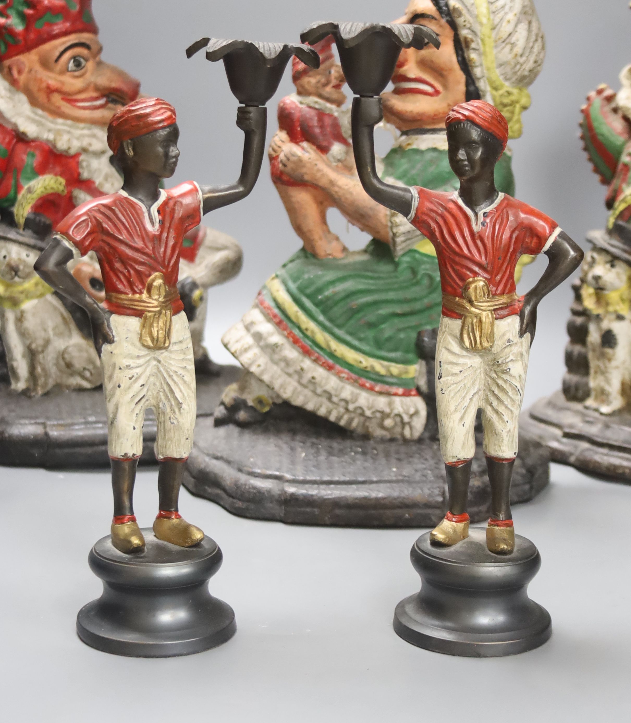 A pair of Victorian cast iron Punch and Judy door stops (later painted), one other and a pair of painted figural cast metal candlesticks, tallest 33cm